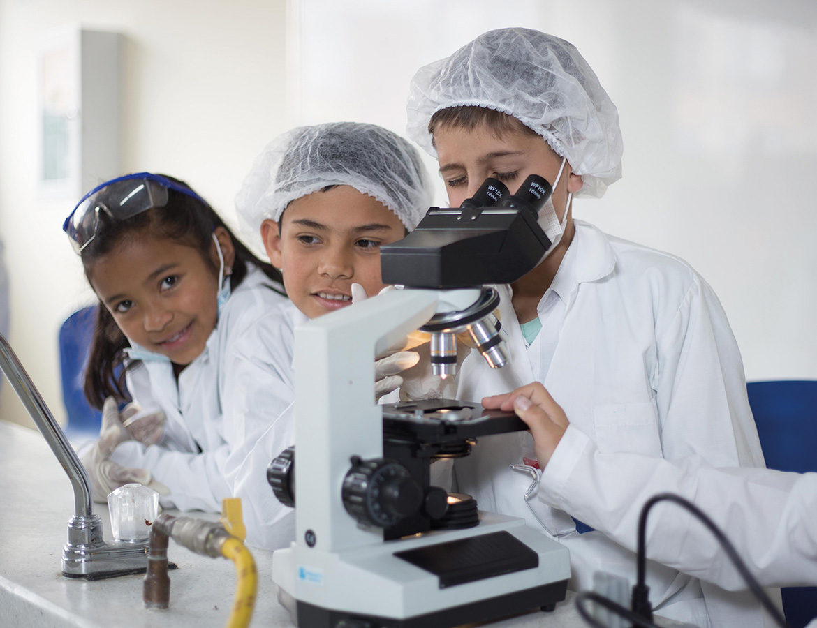 Estudiantes con microscopio en laboratorio de química